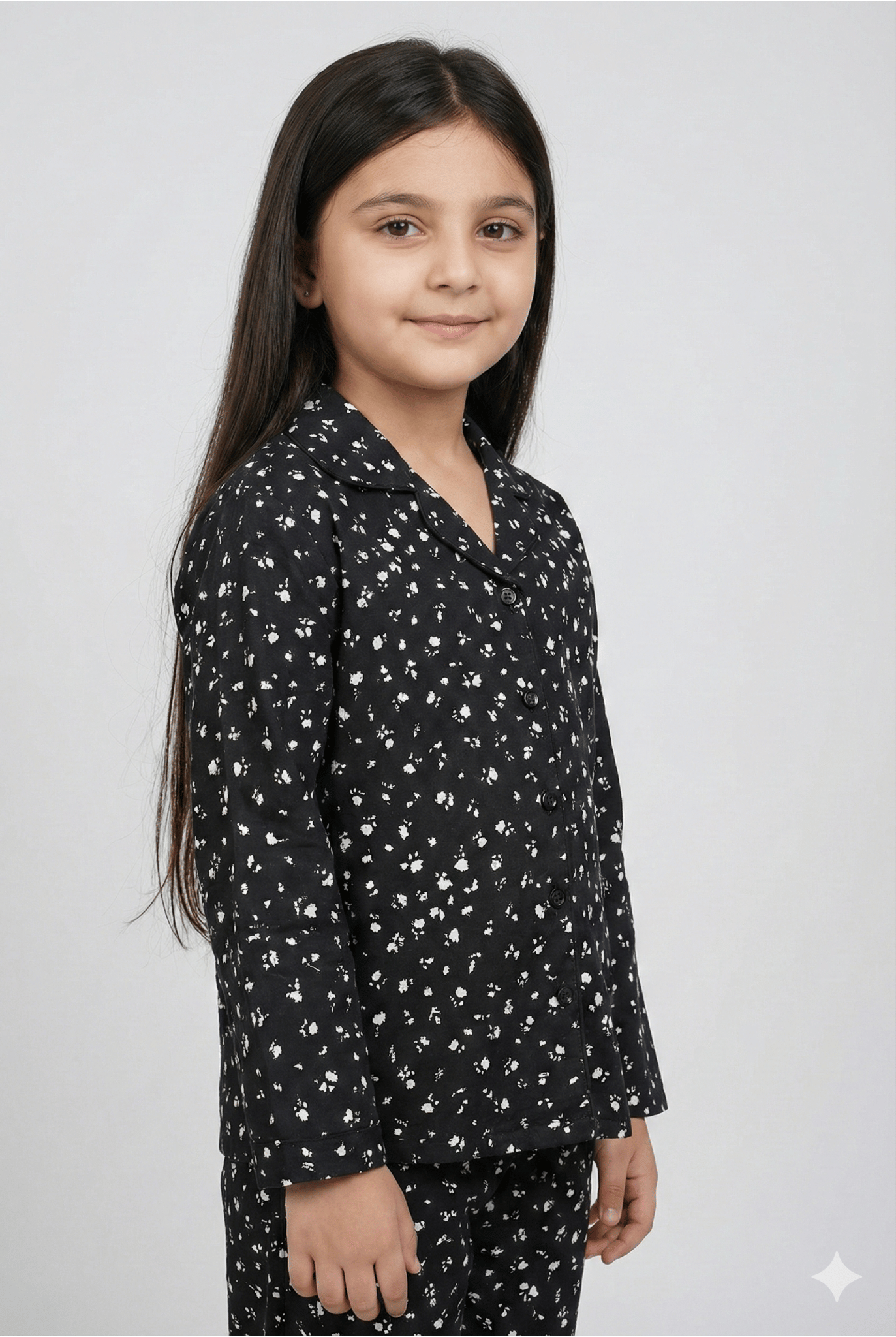 Young girl wearing a black floral patterned outfit on a white background