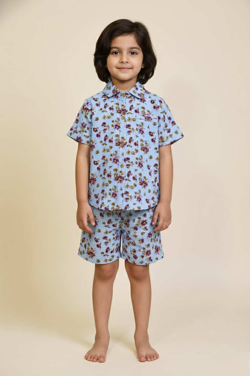 Child wearing a blue floral shirt and shorts set on a beige background
