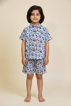 Child wearing a blue floral shirt and shorts set on a beige background