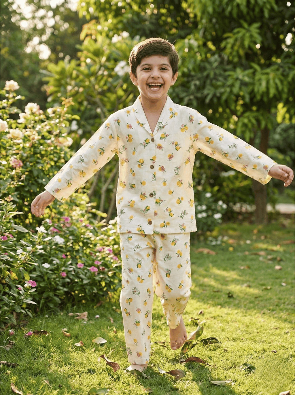 Child in a floral outfit standing in a garden with greenery and flowers in the background